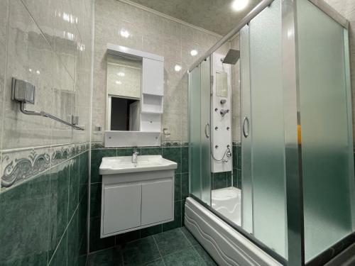 a bathroom with a glass shower and a sink at Mayden Family Apartment in Baku