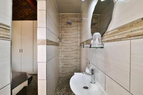 Rudman Townhouses Self-catering Accommodation في بوكسبرغ: حمام مع حوض ومرآة