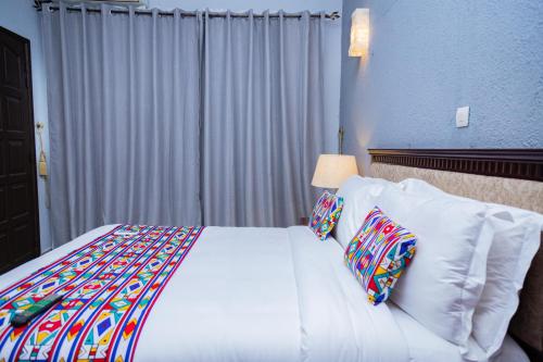 a bedroom with a bed with white sheets and pillows at Hotel Hibiscus Blvd Triomphal in Libreville