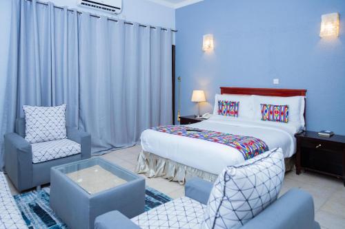 a hotel room with a bed and a chair at Hotel Hibiscus Blvd Triomphal in Libreville