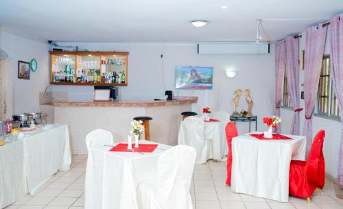 um restaurante com mesas brancas e cadeiras vermelhas em Hotel Hibiscus Blvd Triomphal em Libreville
