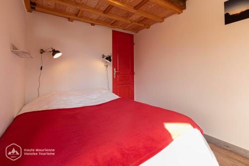 1 dormitorio con puerta roja y 1 cama en Roc de Burel, en Lanslevillard