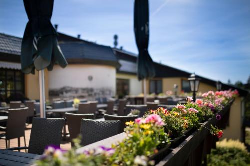 a row of tables and chairs with flowers on a patio at Hotel Forstmeister in Schönheide