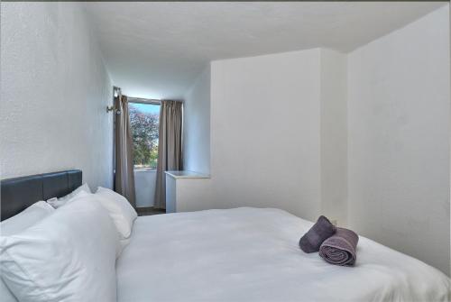 a white bed with two purple pillows on it at Inn & Out Sandton Park in Johannesburg