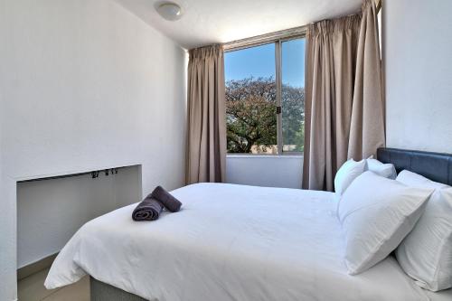 um quarto com uma grande cama branca e uma janela em Inn & Out Sandton Park em Joanesburgo