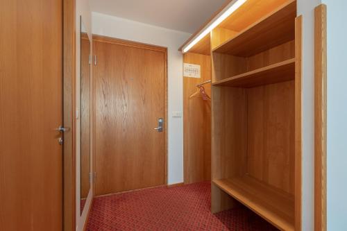 a room with a closet with a door and a red carpet at Raadimõisa Hotell in Tartu
