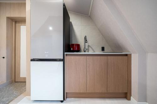 a kitchen with a white refrigerator and a sink at Geoje Mongdol Beach H Avenue Hotel in Geoje 