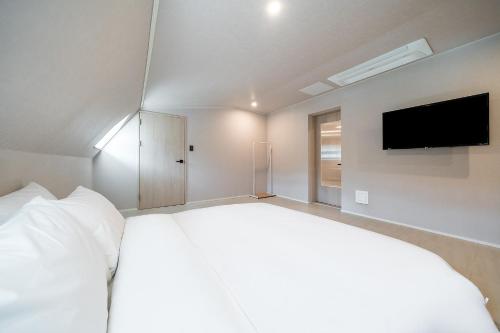 a bedroom with a large white bed and a flat screen tv at Geoje Mongdol Beach H Avenue Hotel in Geoje 