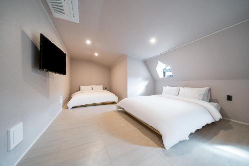 a bedroom with two beds and a flat screen tv at Geoje Mongdol Beach H Avenue Hotel in Geoje 