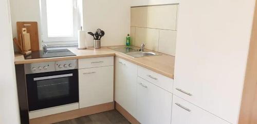a kitchen with white cabinets and a stove and a sink at Ferienwohnung in Cottbus-Klein Ströbitz Nähe Badesee in Cottbus