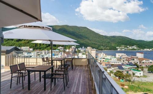 a balcony with tables and chairs and a view of the water at Geoje Mongdol Beach H Avenue Hotel in Geoje 
