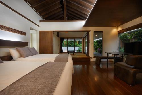 a bedroom with two beds and a living room at Private Villas Ryuz備瀬 in Motobu