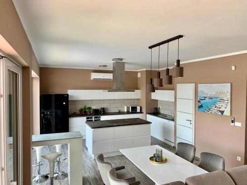 a kitchen with white cabinets and a table and chairs at Finfera Villa in Balatonboglár