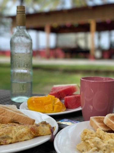 a table with plates of food and a bottle of watermelon and bread at Anda Poseidon’s Beach Resort in Anda