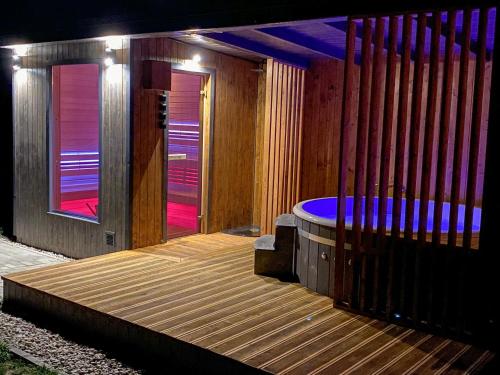 a wooden deck with a hot tub with purple lights at M-MAZURIA Domki letniskowe całoroczne MAZURY GIŻYCKO - z sauną i jacuzzi Fuleda in Fuleda
