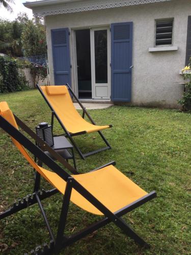 two chairs sitting in the grass in front of a house at Les barbots in Saint-Louis
