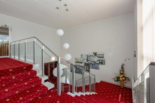 a red carpeted staircase with a glass railing and a red carpet at Raadimõisa Hotell in Tartu