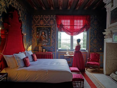 a bedroom with a bed and a woman standing in a window at Relais & Château Louise de La Vallière in Reugny