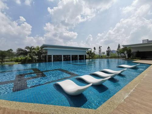 a row of white lounge chairs in a pool at 4 Traders Garden 1 Bedroom Pool View Netflix WiFi in Cheras