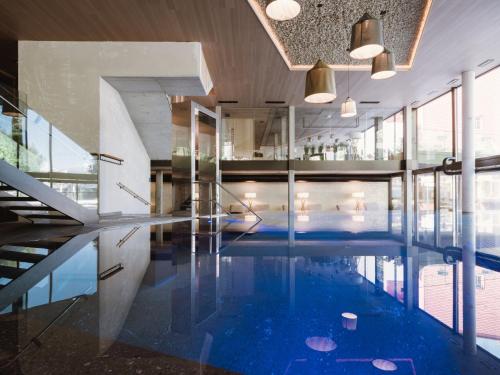 an indoor pool with blue water in a building at Lindenhof Pure Luxury & Spa DolceVita Resort in Naturno