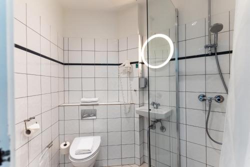 a bathroom with a shower and a toilet and a mirror at Go Hotel Saga in Copenhagen