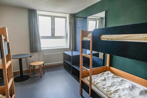 a room with three bunk beds and a window at Jugendherberge Stuttgart International in Stuttgart