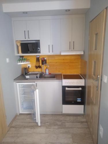 a kitchen with white cabinets and a sink and a stove at Morska Bryza in Chłopy