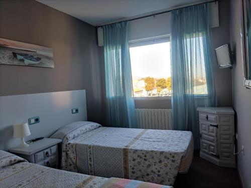 a hotel room with two beds and a window at Albergue Pensión Flavia in Padrón