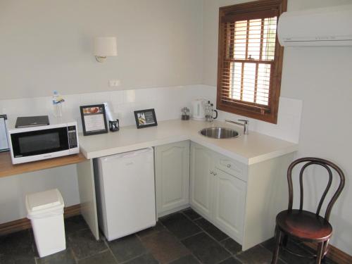 a kitchen with a sink, microwave and refrigerator at Seacombe House Motor Inn Port Fairy in Port Fairy