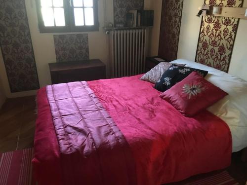 Una cama con una manta rosa y almohadas. en Boutonne Rouge Gite, en Bouin
