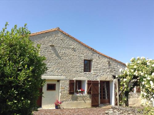 an old stone house with a tree in front of it at Boutonne Rouge Gite in Bouin