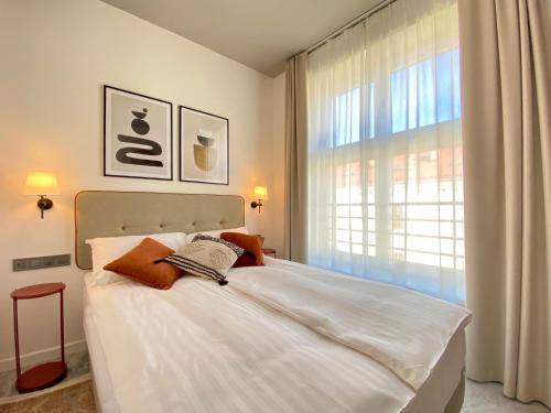 Un dormitorio con una gran cama blanca y una ventana en H11 Aparthotel, en Cracovia