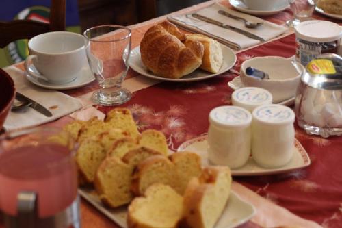 a table with plates of food and cups and bread at Au coeur du Chat Perché in Arnay-le-Duc