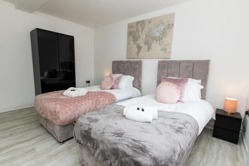 2 camas en una habitación de hotel con almohadas blancas y rosas en K Suites - Flat 110 Fulbridge Road, en Peterborough