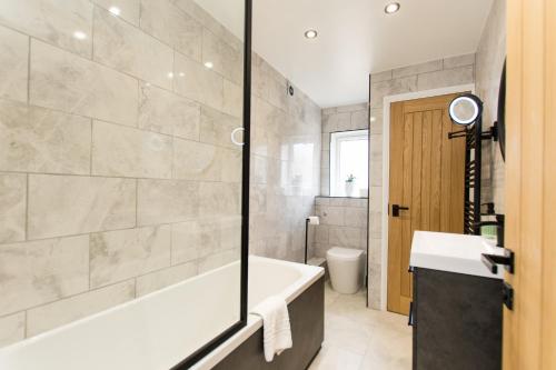 a bathroom with a tub and a sink and a toilet at K Suites - Flat 110 Fulbridge Road in Peterborough