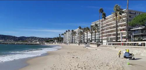 una playa con algunas personas en la arena y edificios en Impeccable 3 pièces avec balcons, la plage à 50m en Antibes