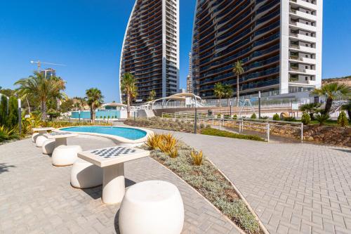 een park met banken en gebouwen in een stad bij SUNSET WAVES blue sky apartment in Benidorm