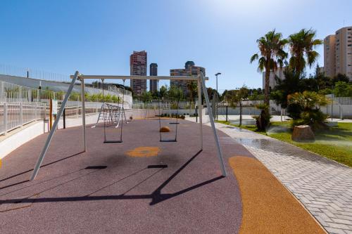 an empty playground in a park with buildings in the background at SUNSET WAVES blue sky apartment in Benidorm