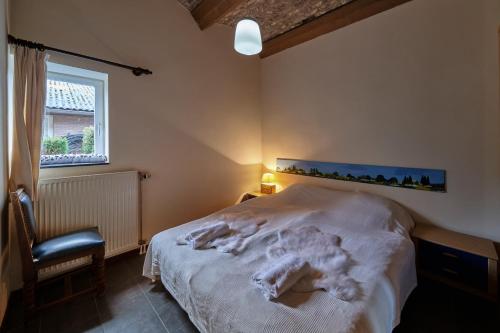 a bedroom with a bed and a chair and a window at Meschermolen 8 in Eijsden