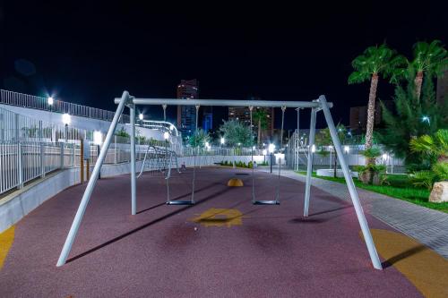 an empty swing set in a park at night at SUNSET WAVES blue sky apartment in Benidorm