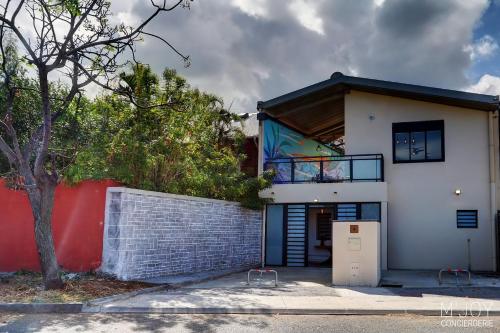 a white house with a red wall and a tree at TIGOUYA - Maison 135m2 - 2 ch et Jacuzzi in Saint-Leu