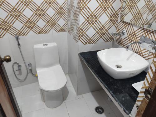 a bathroom with a white toilet and a sink at Hotel Surya Excellency By WB Inn in Jammu