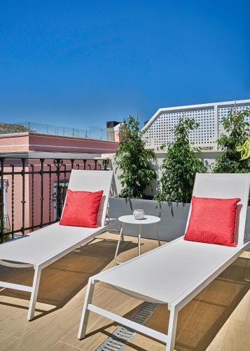 two white chairs on a balcony with red pillows at Vincci Molviedro Suites Apartments in Seville