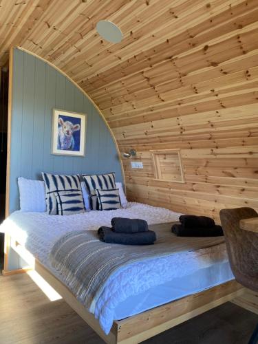 Bett in einem Zimmer mit Holzdecke in der Unterkunft Craigend Farm Holiday Pods - The Woolly Sheep in Dumfries