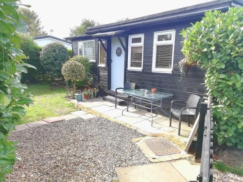 una pequeña casa negra con una mesa en un patio en 2 bedroom chalet bungalow on Humberston Fitties. en Humberston