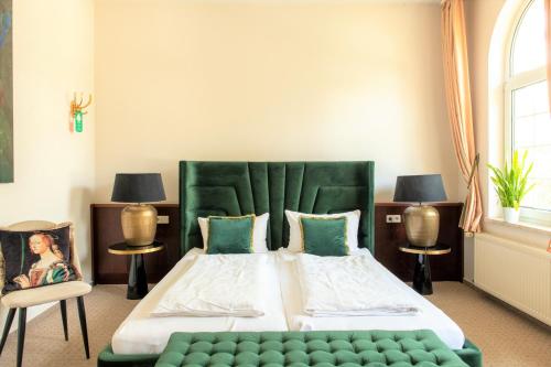 a bedroom with a large bed with a green headboard at Hotel & Restaurant Raueneck in Bad Saarow