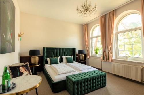 a bedroom with a green bed and a table at Hotel Villa Raueneck in Bad Saarow