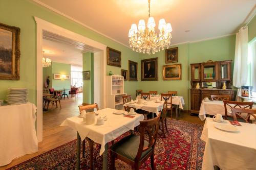 a dining room with tables and chairs and a chandelier at Hotel & Restaurant Raueneck in Bad Saarow