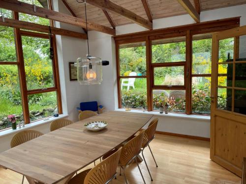 uma sala de jantar com uma grande mesa de madeira e janelas em Dejligt hus på landet em Give