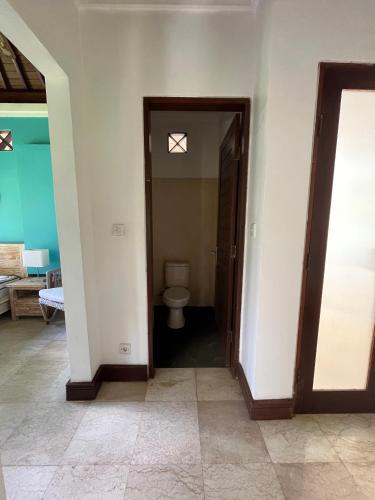 a bathroom with a toilet and a door to a room at Balian Bliss Retreat Bungalow & Villas in Balian